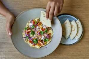 Overhead shot of tasty fine vegetarian plant-based international cuisine on artisanal ceramic plate including naan bread, tomatoes and herbs for mindful eating and a nutritious plant based diet.