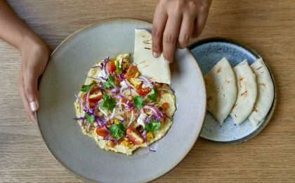 Overhead shot of tasty fine vegetarian plant-based international cuisine on artisanal ceramic plate including naan bread, tomatoes and herbs for mindful eating and a nutritious plant based diet.