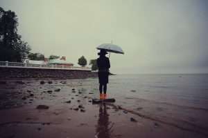   woman with an umbrella by the sea wind rain
