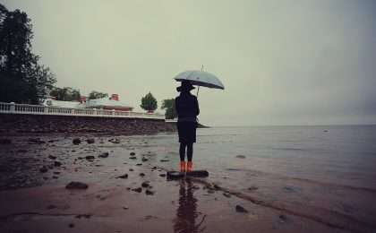 woman with an umbrella by the sea wind rain